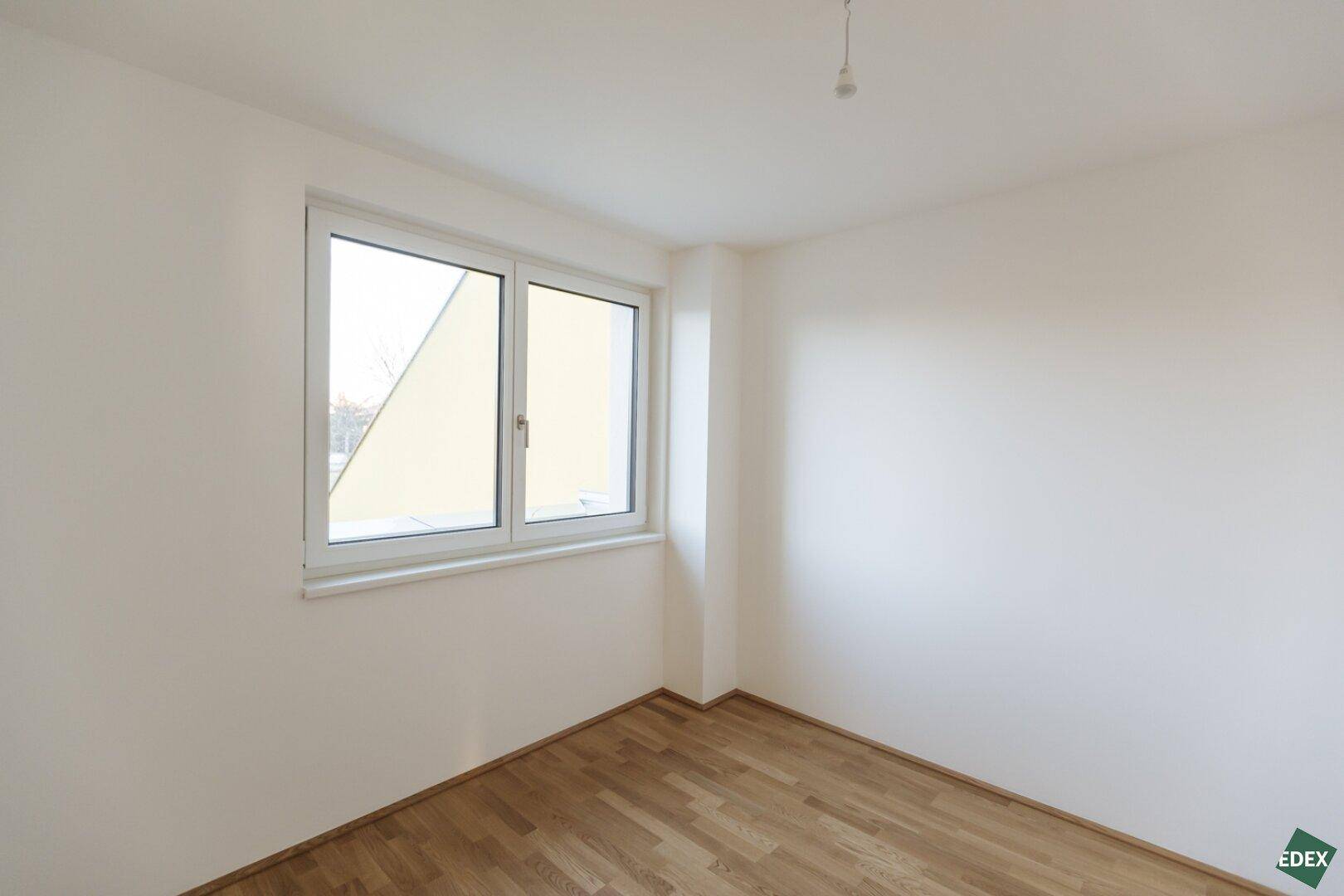 Helles Zimmer mit Holzboden und Fenster, ideal als Kinder- oder Arbeitszimmer.