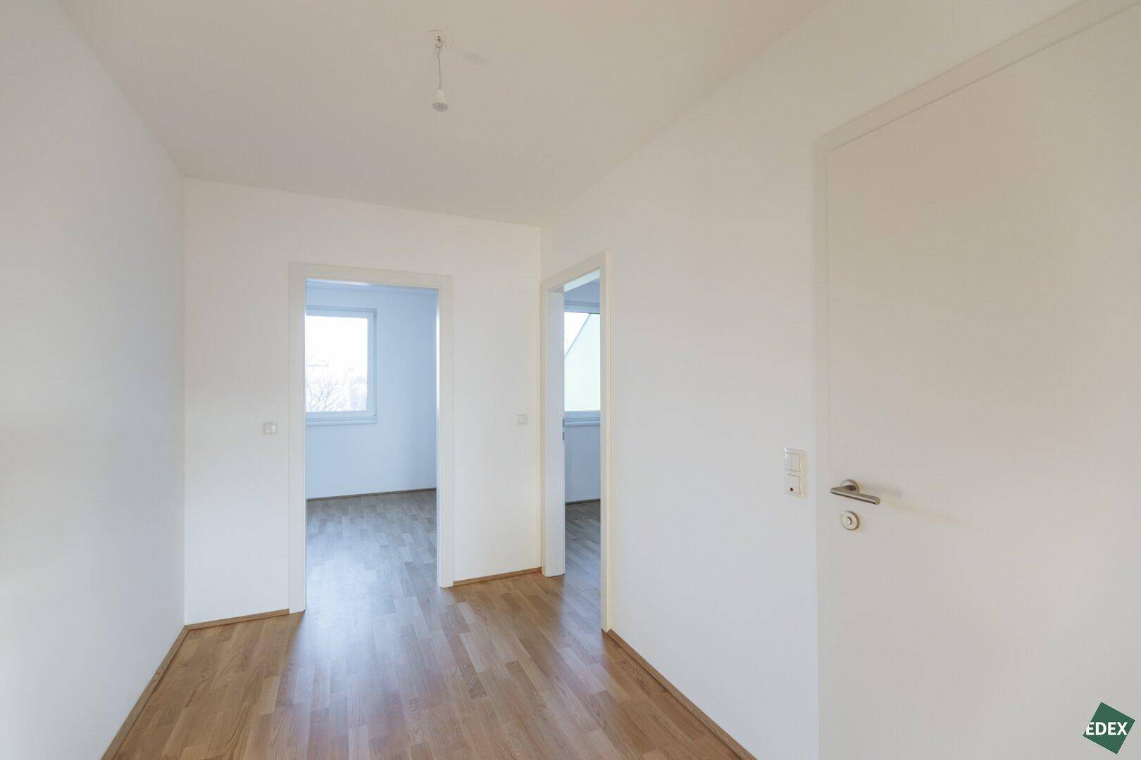 Heller Flur mit Holzboden und Zugang zu weiteren Räumen.
