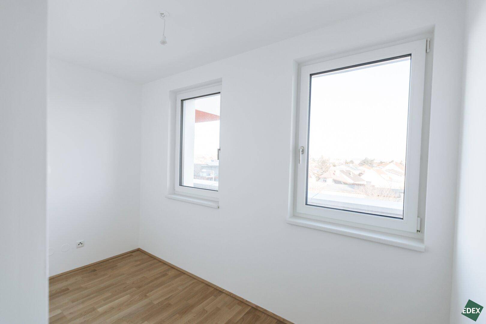 Helles Zimmer mit zwei Fenstern und Parkettboden, ideal als Schlaf- oder Arbeitszimmer.