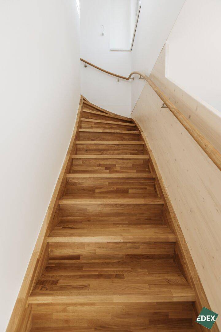 Elegante Holztreppe mit passendem Holzgeländer, die in die obere Etage des Hauses führt.