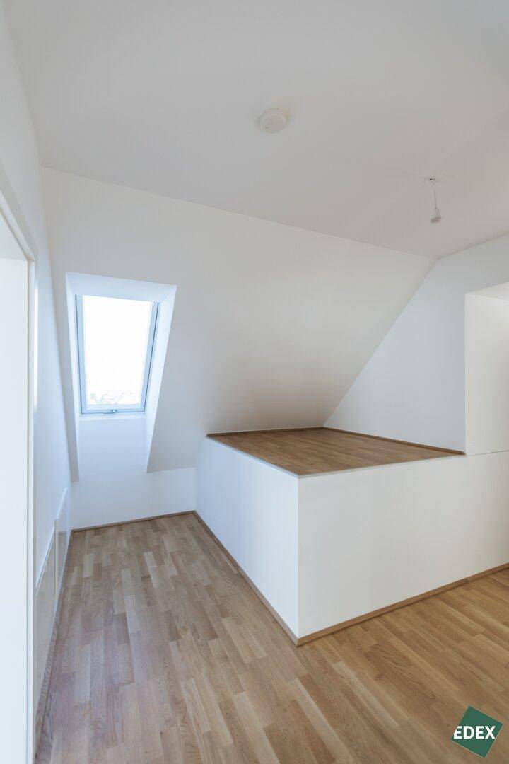 Dachgeschossraum mit schrägem Dachfenster und erhöhtem Bereich, bietet vielseitige Nutzungsmöglichkeiten.