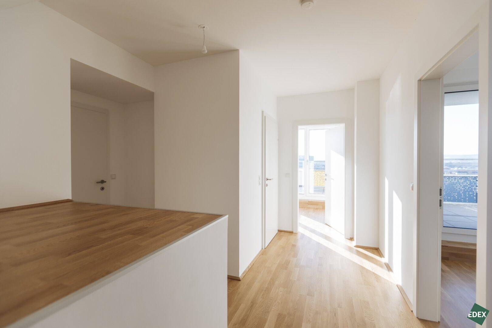 Heller Flur mit Holzboden und Zugang zu verschiedenen Räumen, durchflutet von natürlichem Licht.