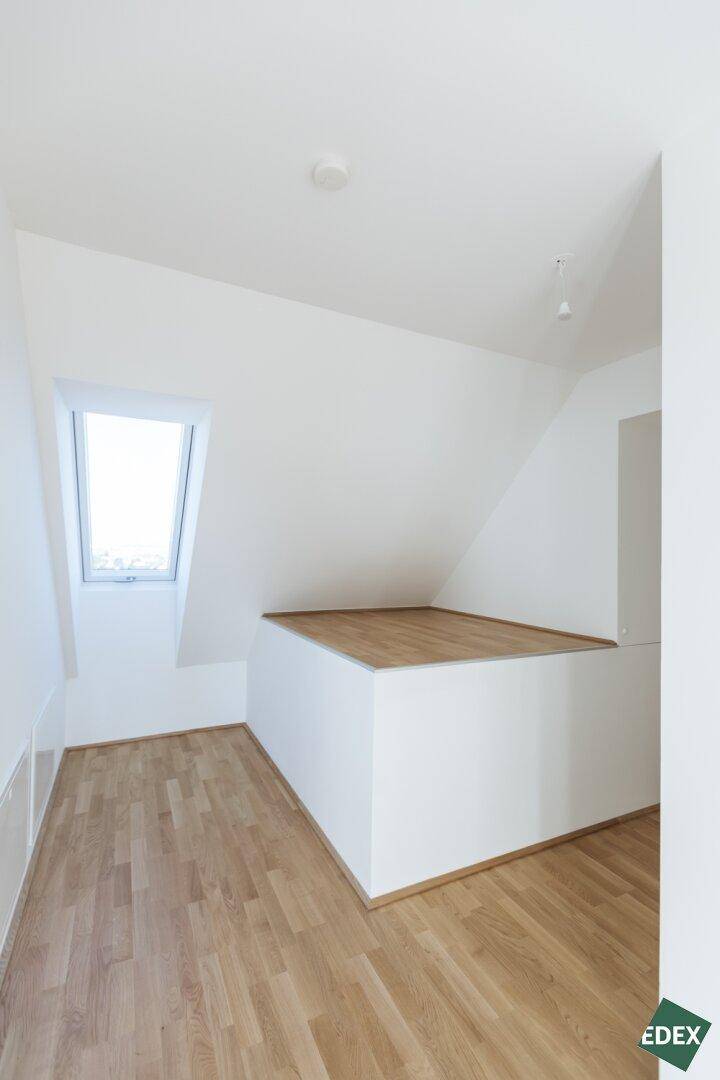Dachgeschossraum mit schrägem Dachfenster und erhöhtem Bereich, bietet vielseitige Nutzungsmöglichkeiten.