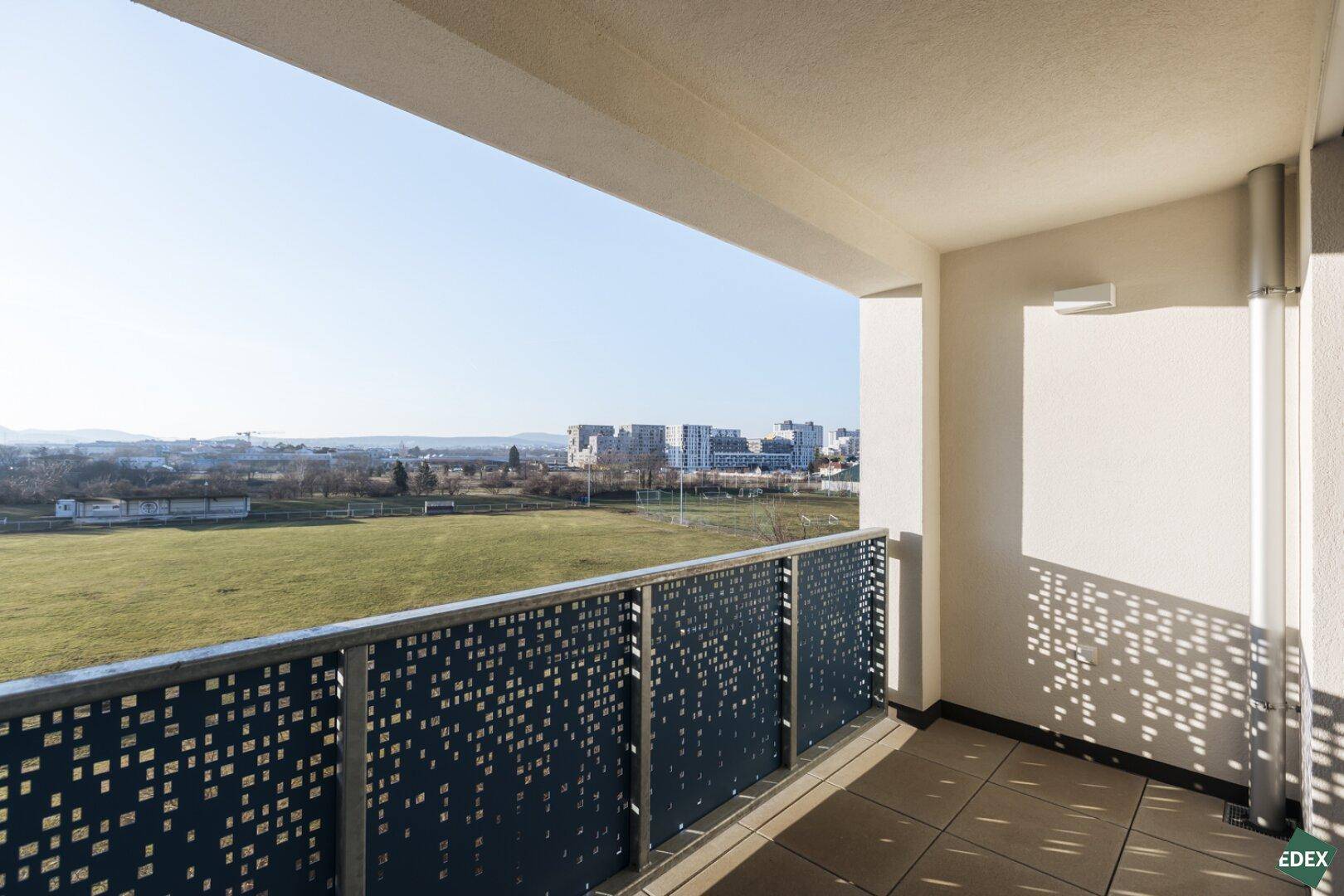 Überdachter Balkon mit modernem Lochblechgeländer und weitem Blick über die Landschaft.