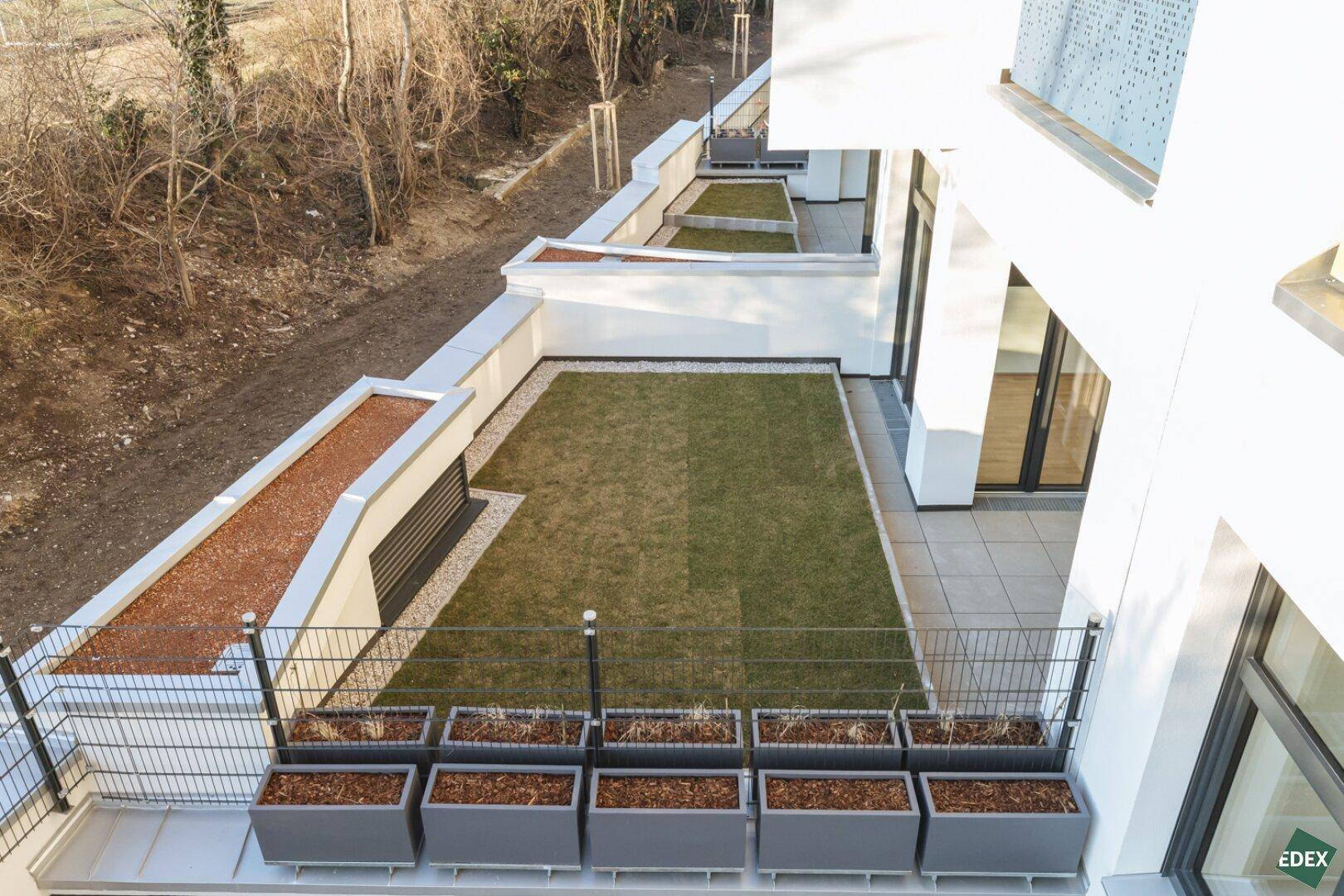 Kleine private Gartenfläche mit Rasen und Pflanzkübeln, zugänglich von der Terrasse.