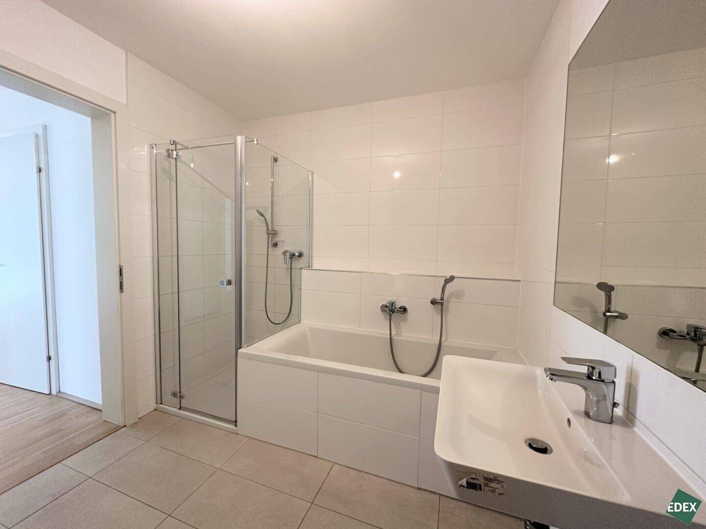 Modernes Badezimmer mit Badewanne, Duschabtrennung und einem einzelnen Waschbecken.