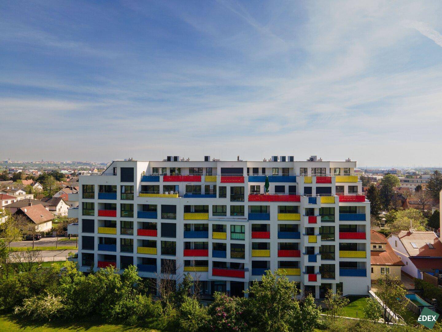 Luftaufnahme des Wohnkomplexes mit lebhaften, farbigen Balkonen und umliegender Bebauung.