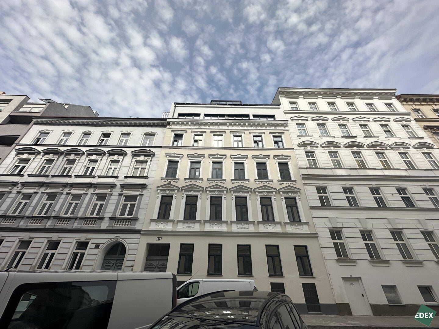 Historische Fassade eines Mehrfamilienhauses mit klassischen Fenstern und städtischem Flair.