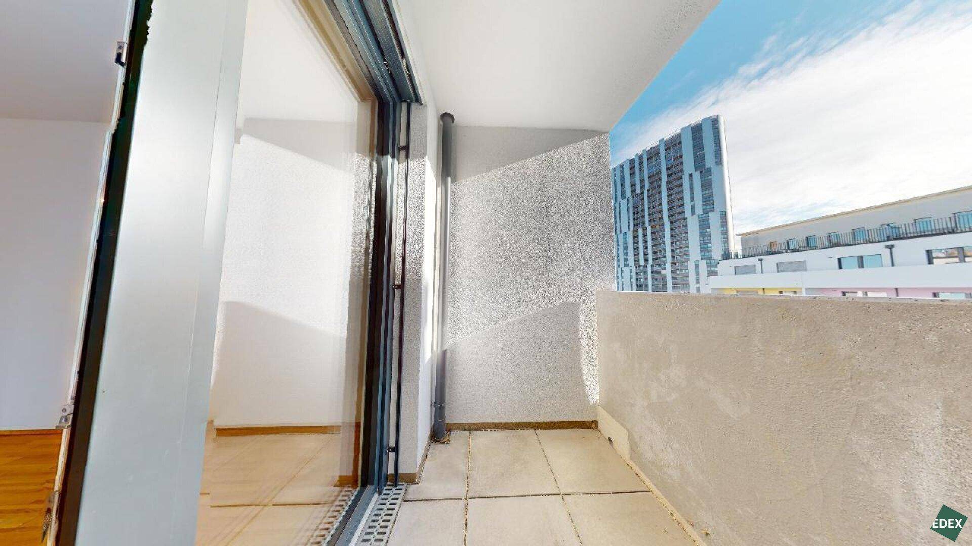 Balkon mit Fliesenboden und Blick auf moderne Hochhäuser in der Stadt.