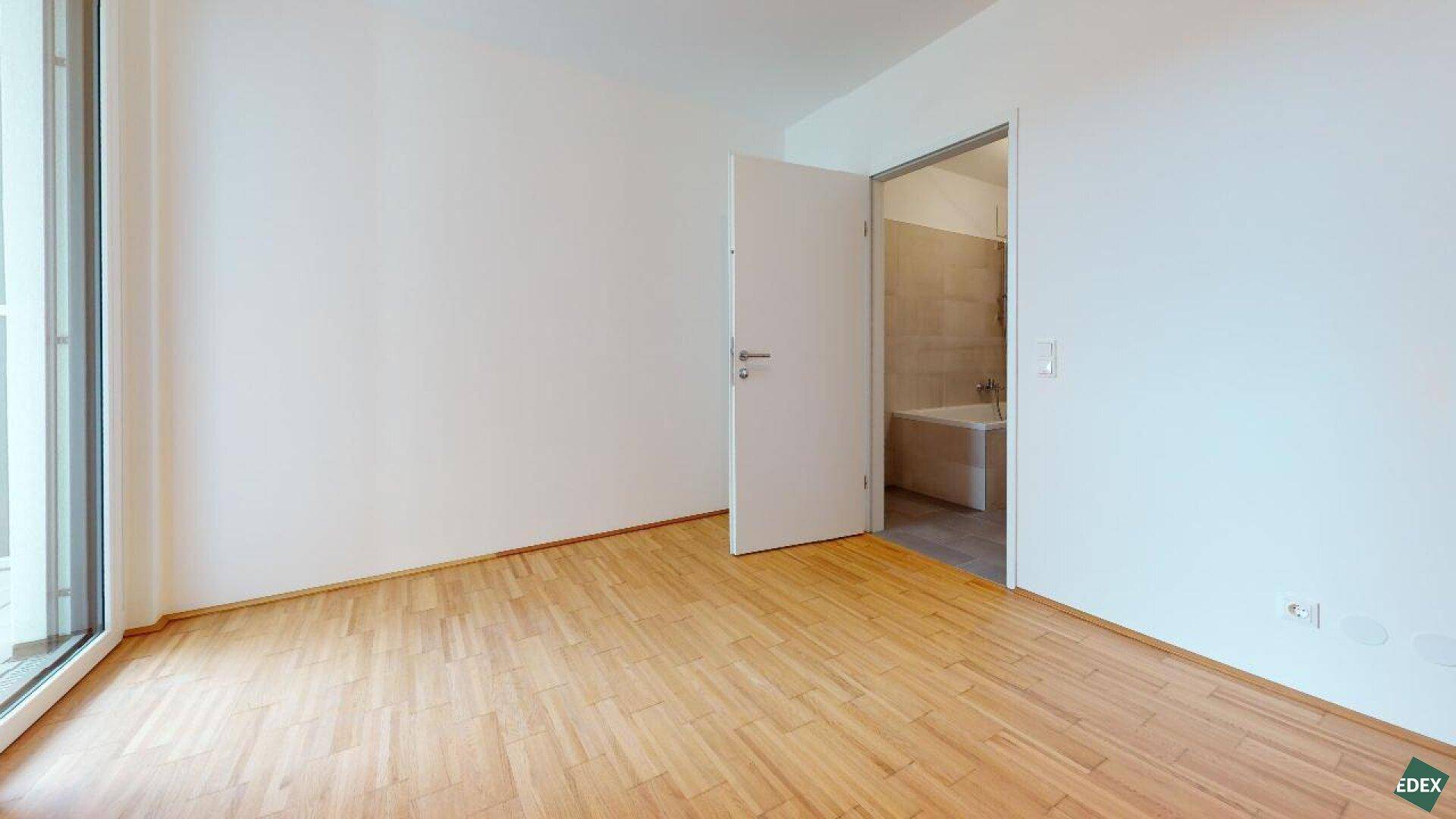 Geräumiges Zimmer mit Parkettboden und direktem Zugang zu einem Badezimmer.