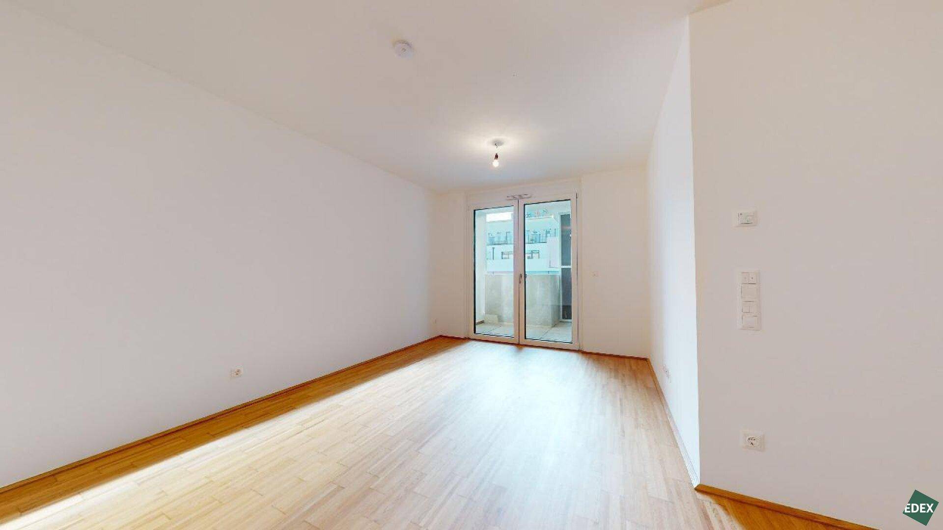 Heller Raum mit Parkettboden und Zugang zu einem Außenbereich, ideal als Schlafzimmer.