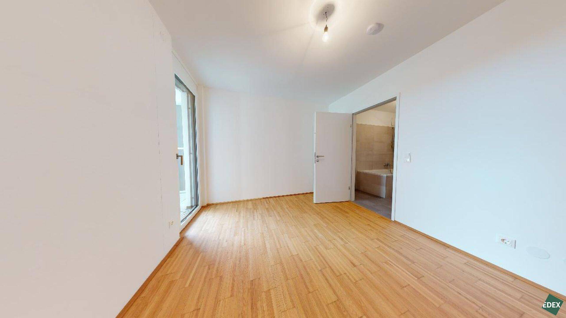 Freundliches Zimmer mit Parkettboden und direktem Zugang zu einem modernen Badezimmer.