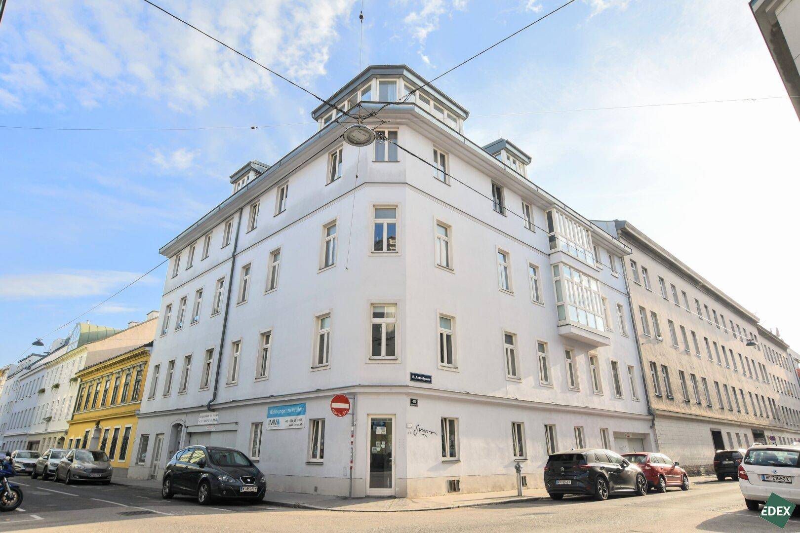 Eckgebäude mit klassischer Architektur und mehreren Etagen an einer städtischen Straße.