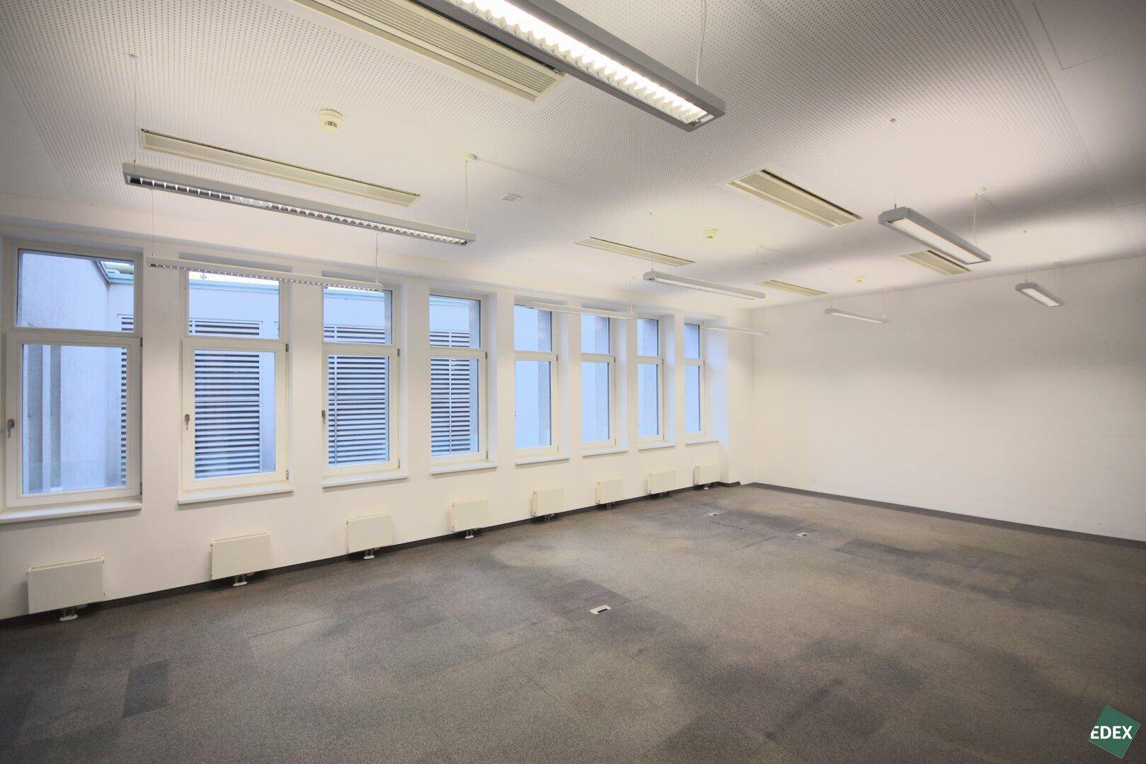Helles Büro mit vielen Fenstern und Teppichboden, bietet viel Tageslicht für eine angenehme Arbeitsatmosphäre.
