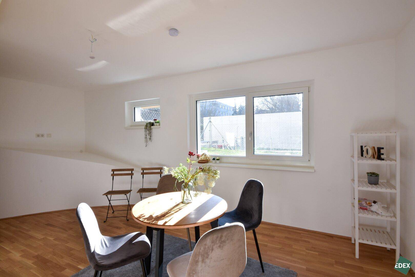 Heller Essbereich mit Holzboden, Fenster und schrägen Wänden, bietet Platz für gesellige Runden.