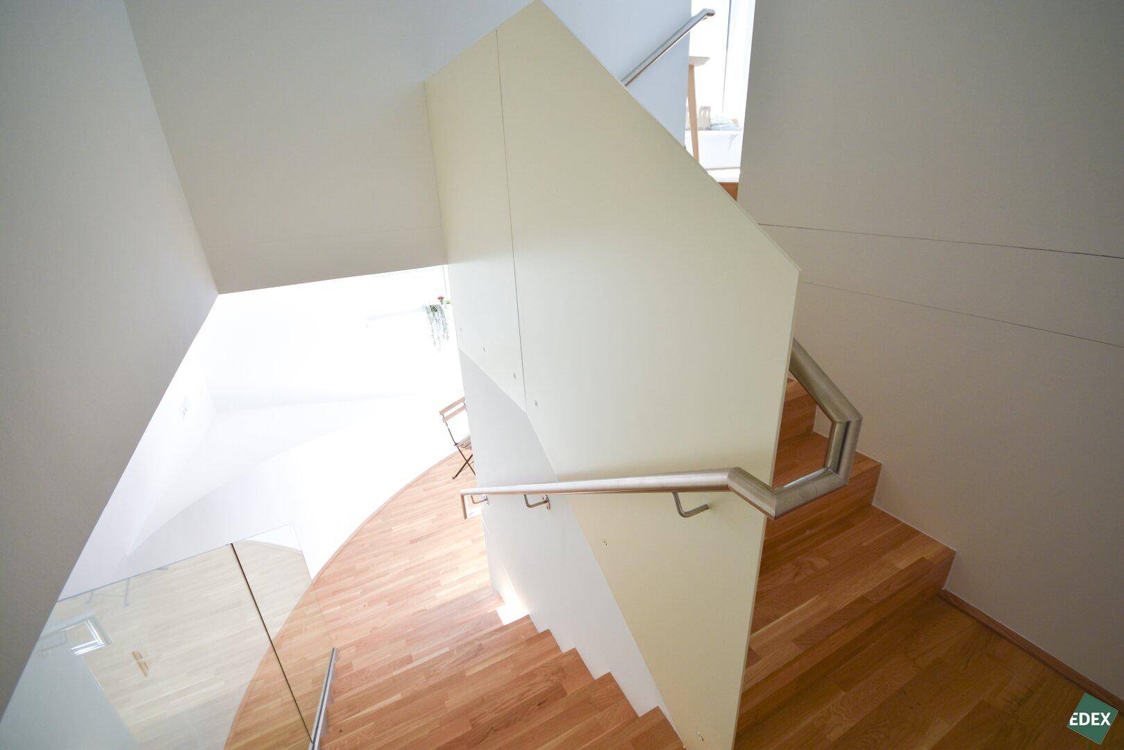 Wendeltreppe mit Holzstufen und modernem Geländer, verbindet die Stockwerke elegant.