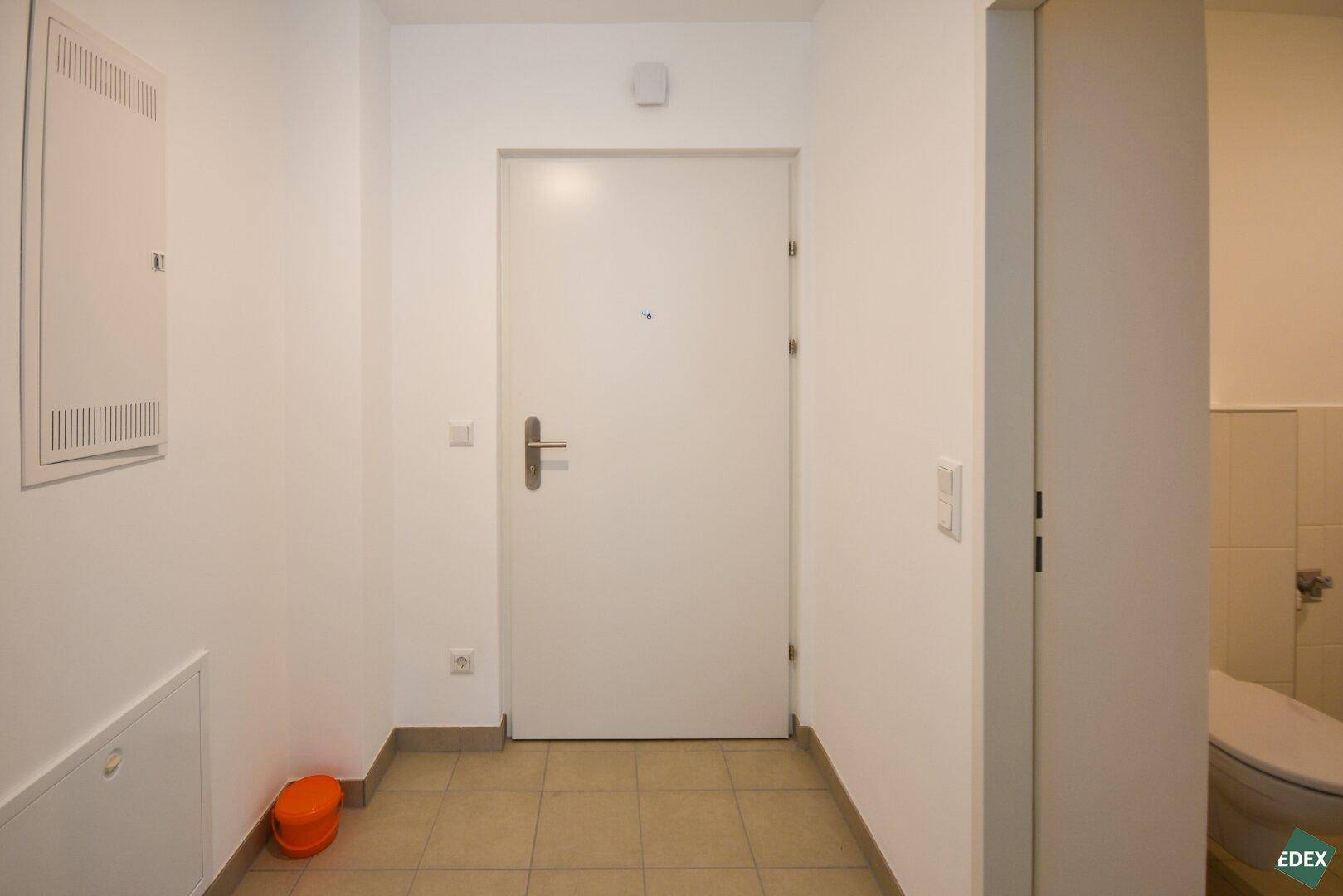 Eingangsbereich mit Fliesenboden, weißer Tür und Sicherungskasten, sauber und funktional.