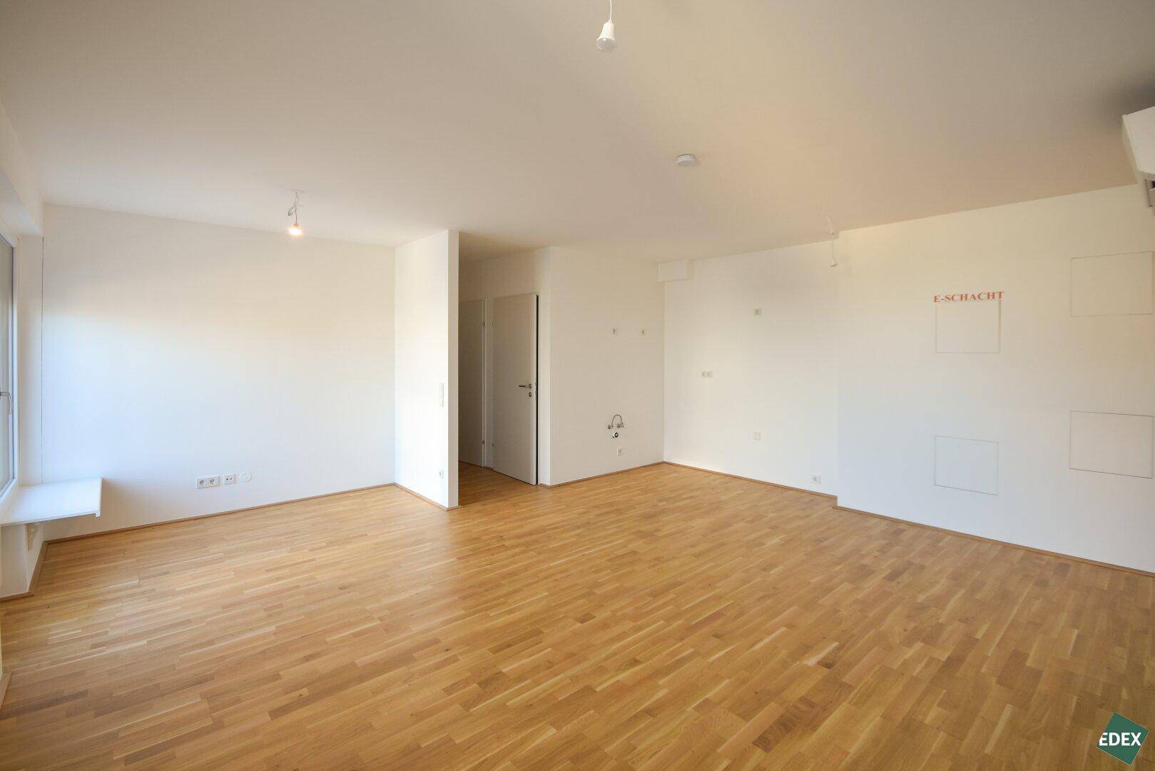 Leerer Wohnraum mit Holzboden und weiß gestrichenen Wänden, ideal für neue Einrichtungsideen.