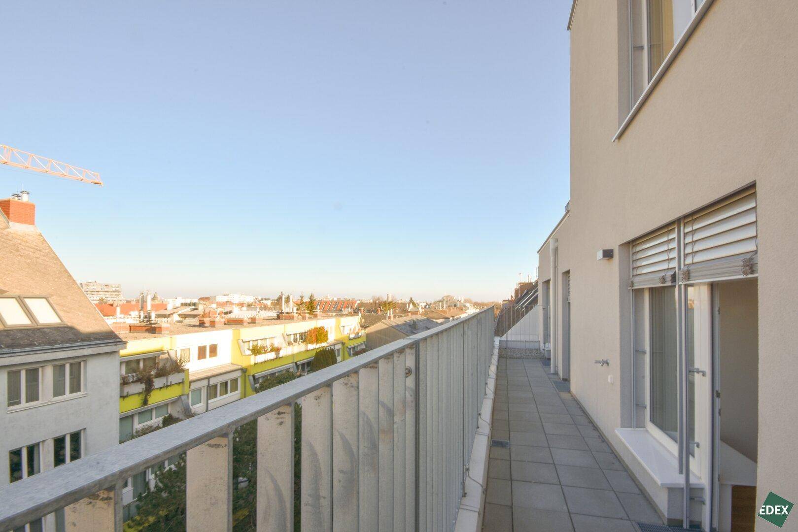 Langer Balkon mit Metallgeländer und Blick über die städtische Umgebung.