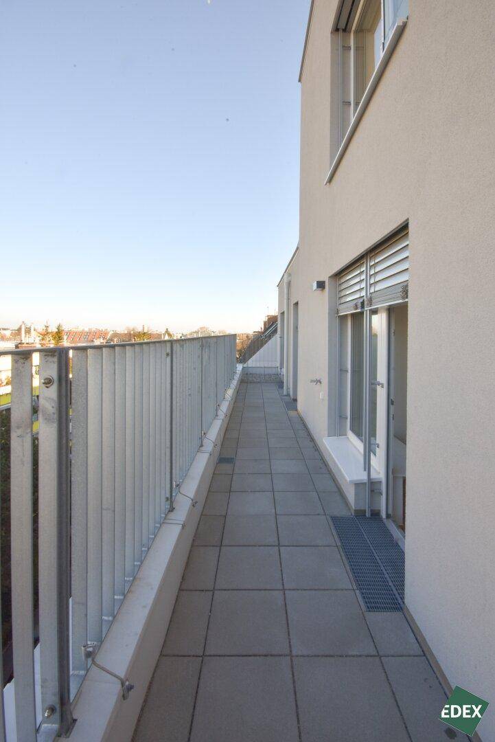 Schmaler Balkon mit Fliesenboden und Metallgeländer, bietet einen Blick auf die Umgebung.