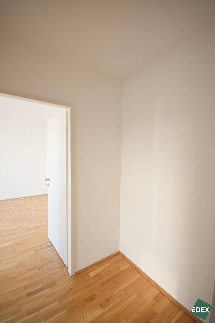 Heller Flur mit Holzboden und weiß gestrichenen Wänden, verbindet die verschiedenen Räume.