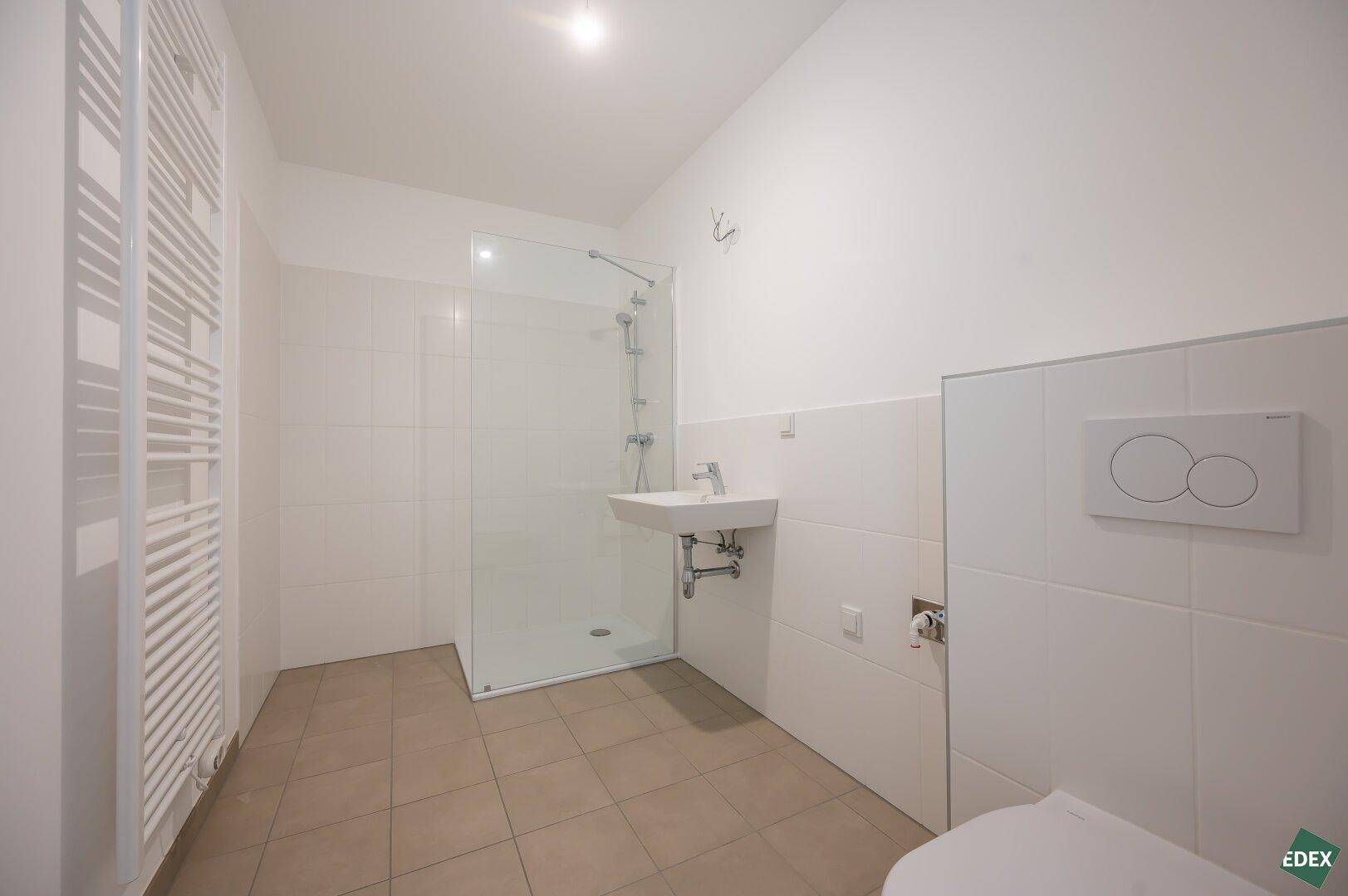 Modernes Badezimmer mit ebenerdiger Dusche, Wand-WC und beheiztem Handtuchhalter.