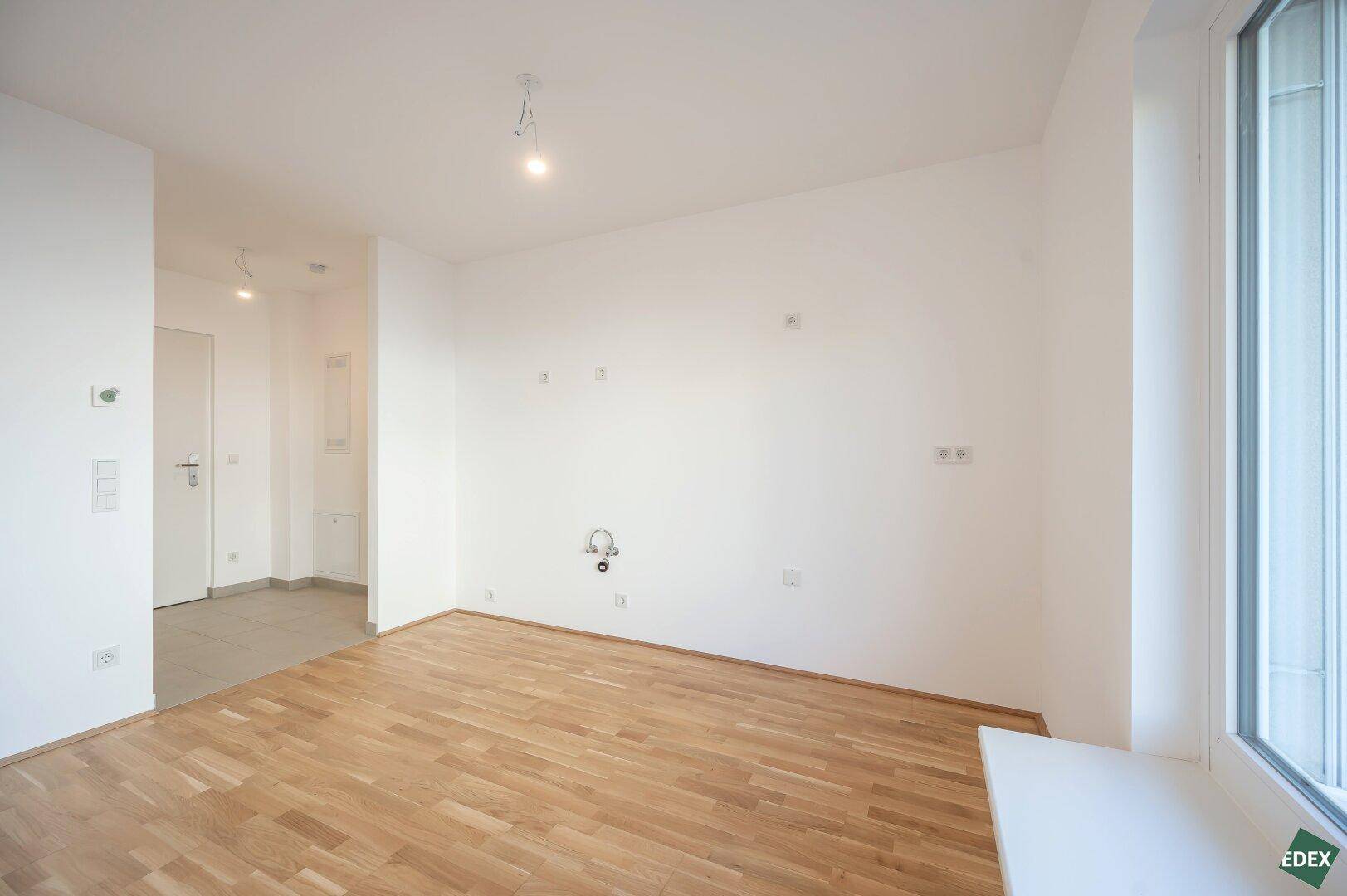 Leerer Raum mit Parkettboden, weißen Wänden und Fenster, bereit zur individuellen Gestaltung.
