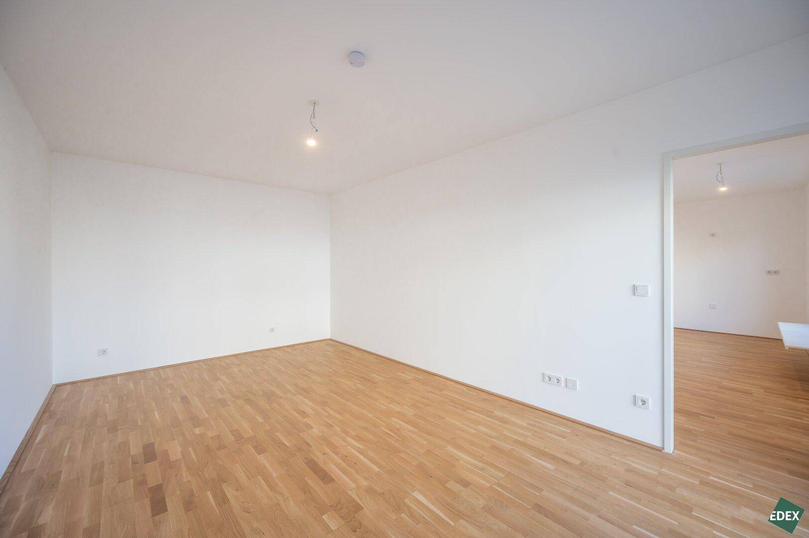 Geräumiger, heller Raum mit Parkettboden und weiß gestrichenen Wänden, ideal für Wohnzwecke.