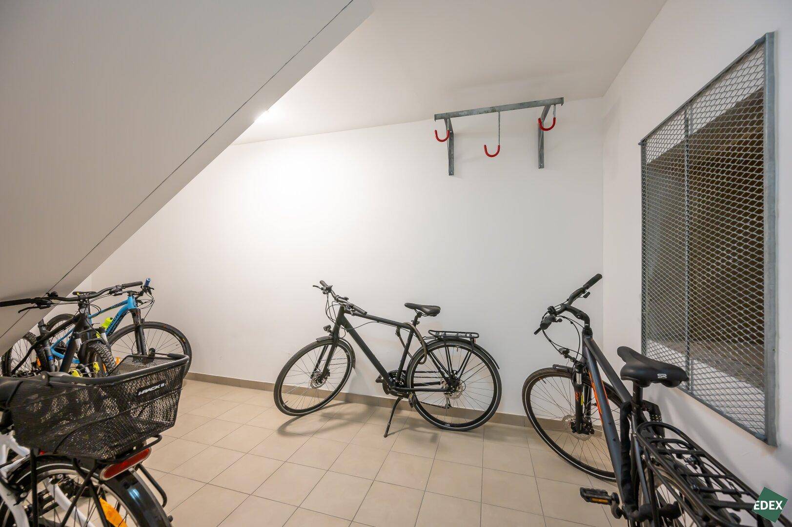 Heller Fahrradraum mit Fliesenboden und Wandhalterungen für Fahrräder, sauber und funktional.