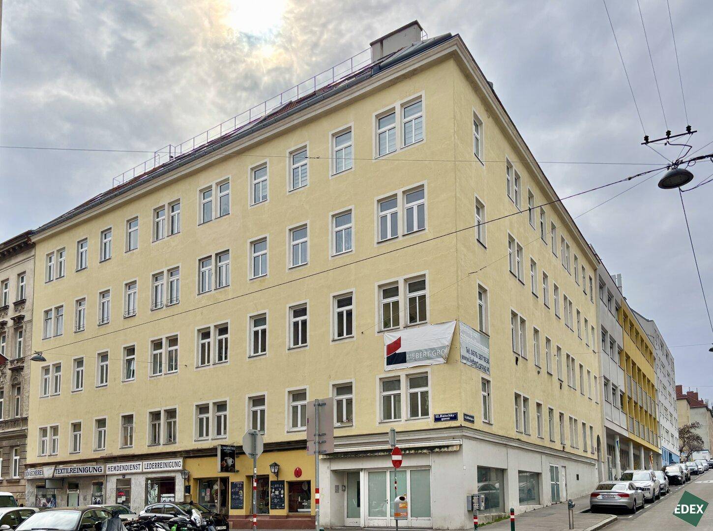 Mehrstöckiges Gebäude mit gelber Fassade an einer Straßenecke in der Stadt.