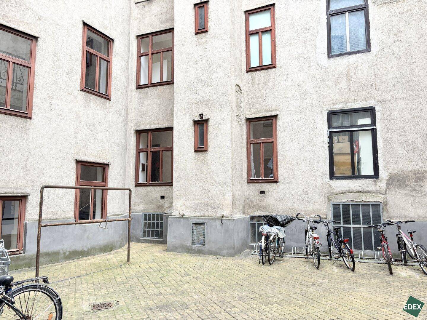 Innenhof eines Altbaus mit gepflastertem Boden und abgestellten Fahrrädern.