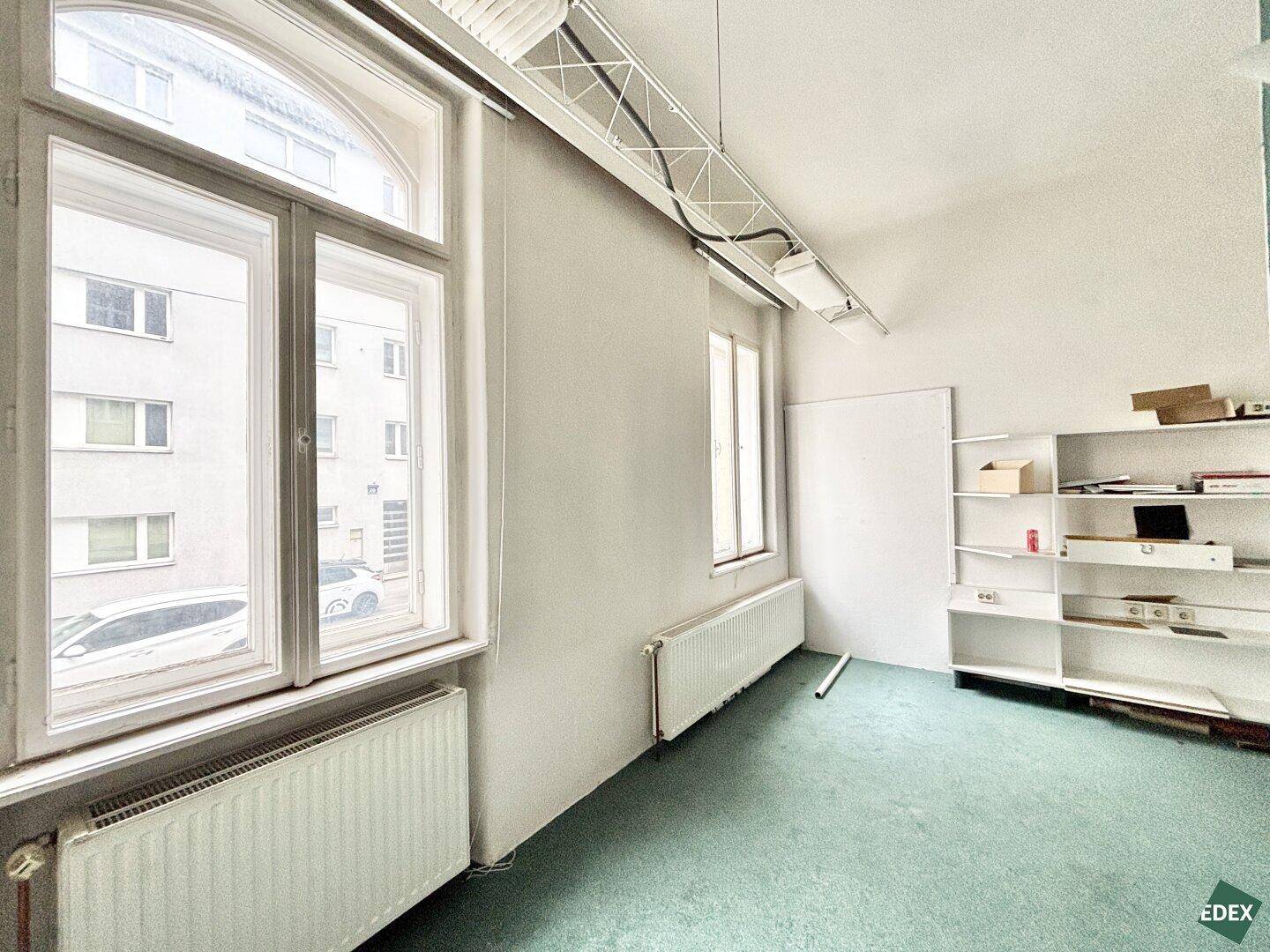 Geräumiger Büroraum mit großen Fenstern und Blick auf die Straße.