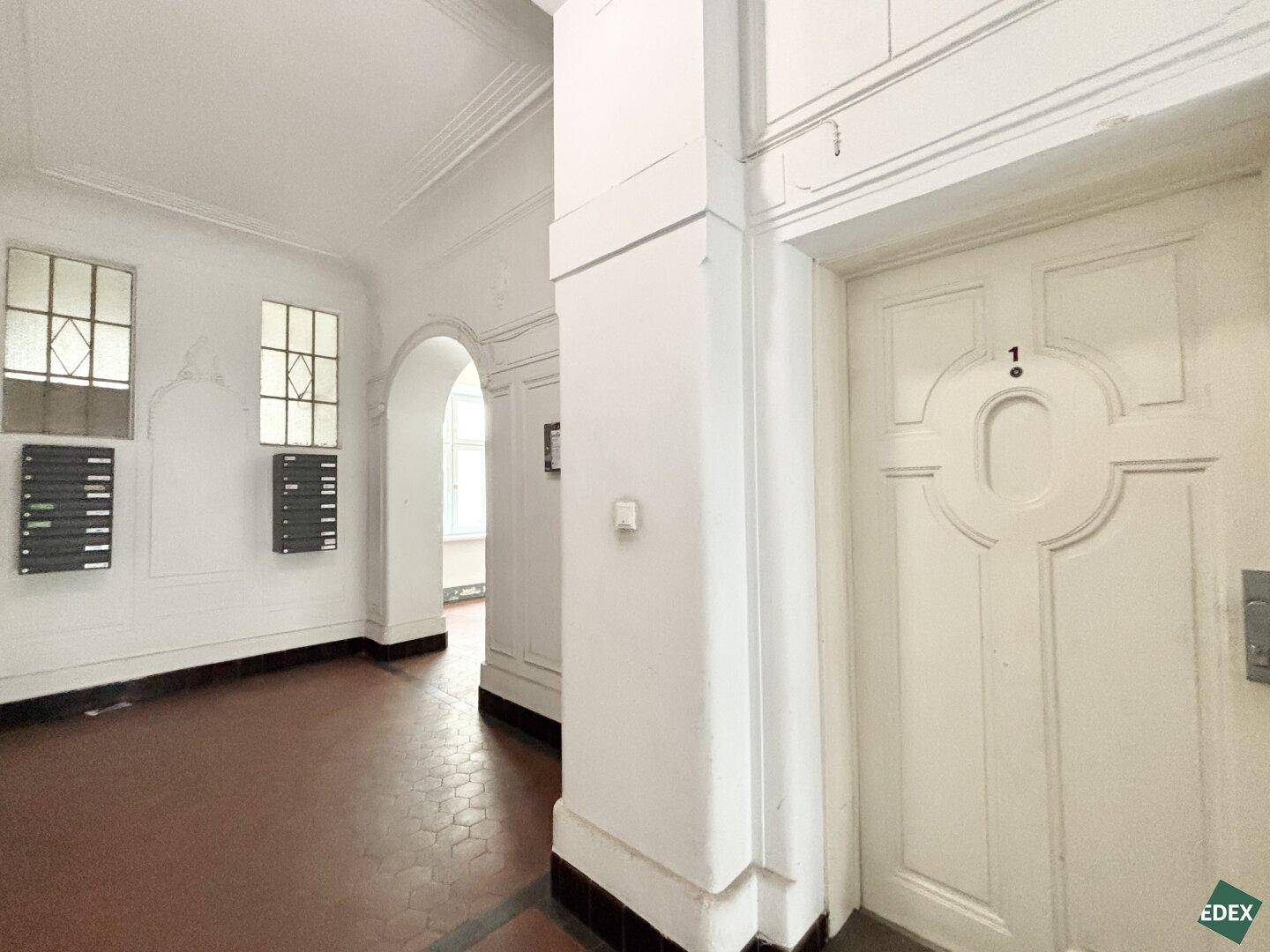 Eingangsbereich eines Altbaus mit Terrakottafliesen und historischen Details.