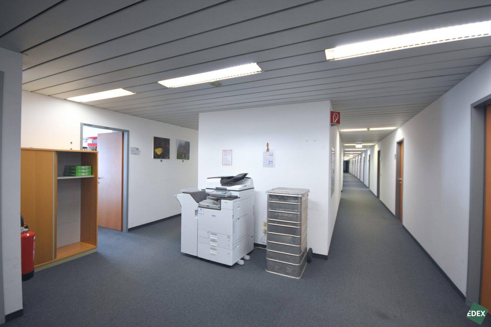 Breiter Bürogang mit Kopierstation und Türen zu weiteren Büroräumen.