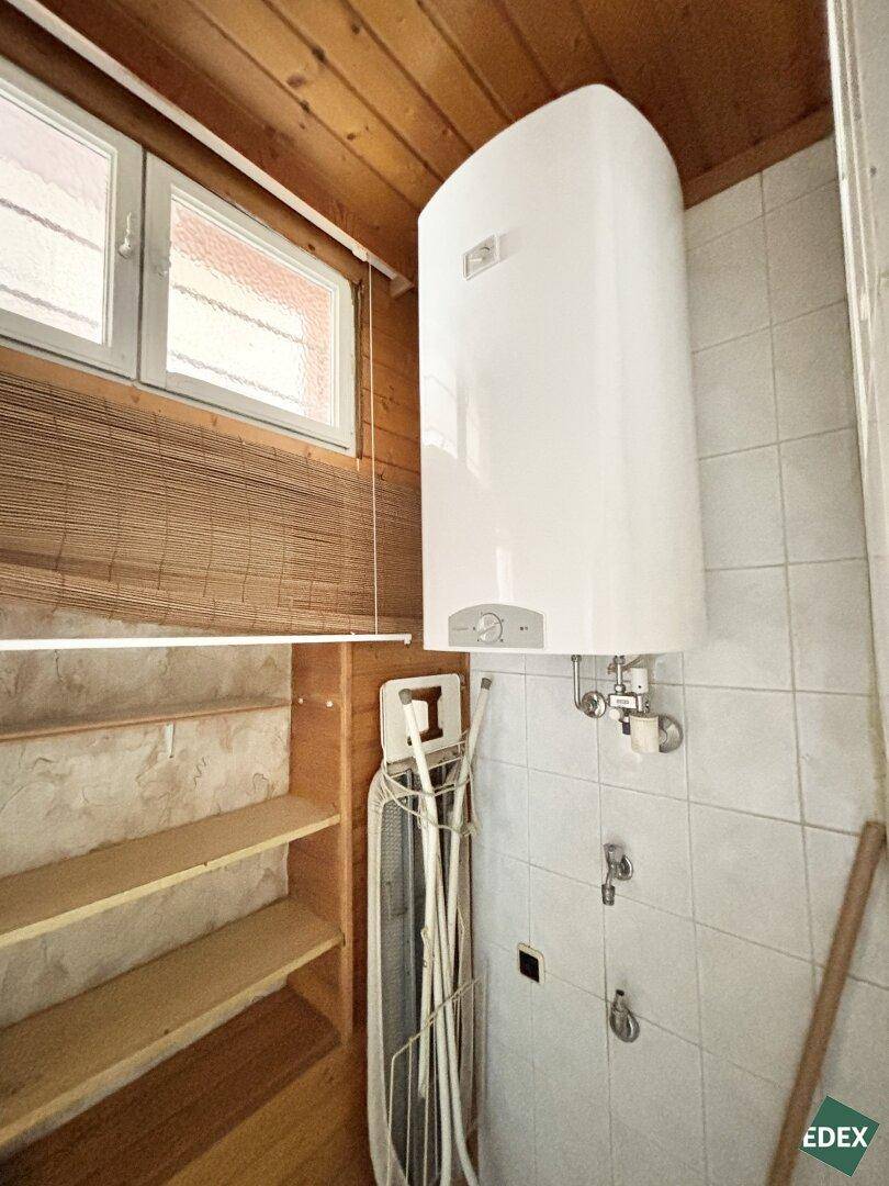 Kleiner Toilettenbereich mit Fenster und Holzvertäfelung, angrenzend an das Badezimmer.