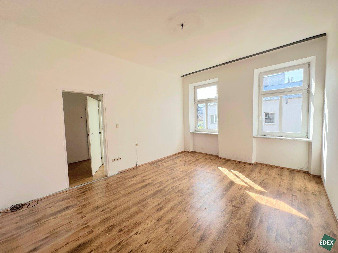 Geräumiges Zimmer mit Laminatboden und Zugang zu einem weiteren Raum, hell und einladend.