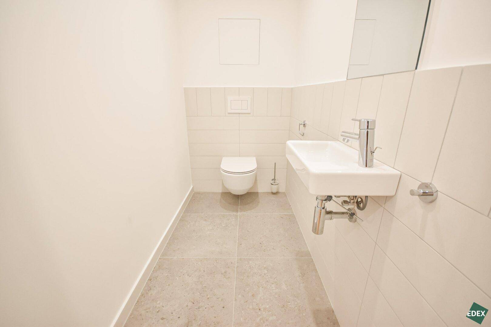 Separates Gäste-WC mit wandhängender Toilette und modernem Waschbecken.