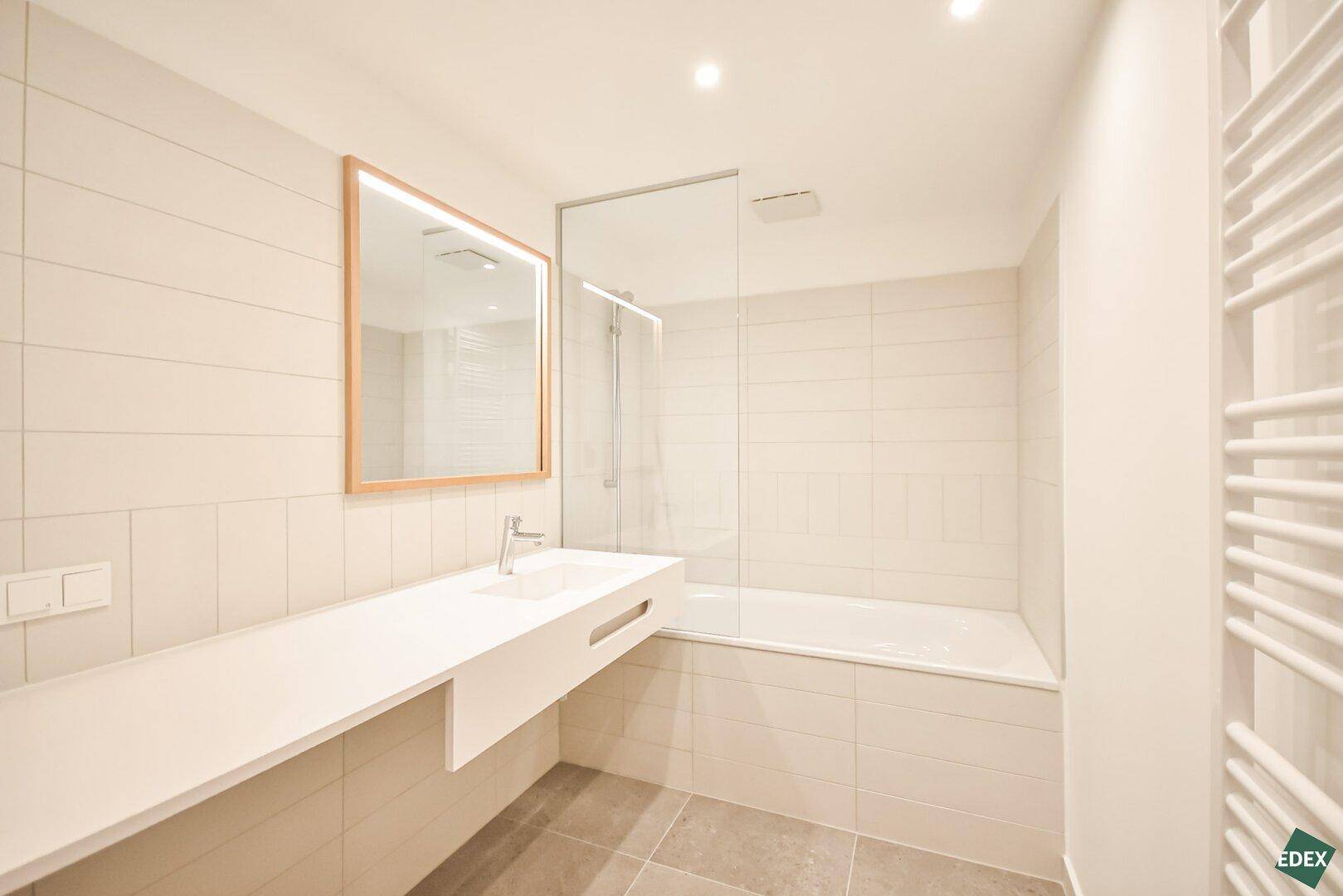 Modernes Badezimmer mit Badewanne, Dusche und einem einzelnen Waschbecken mit Spiegel.