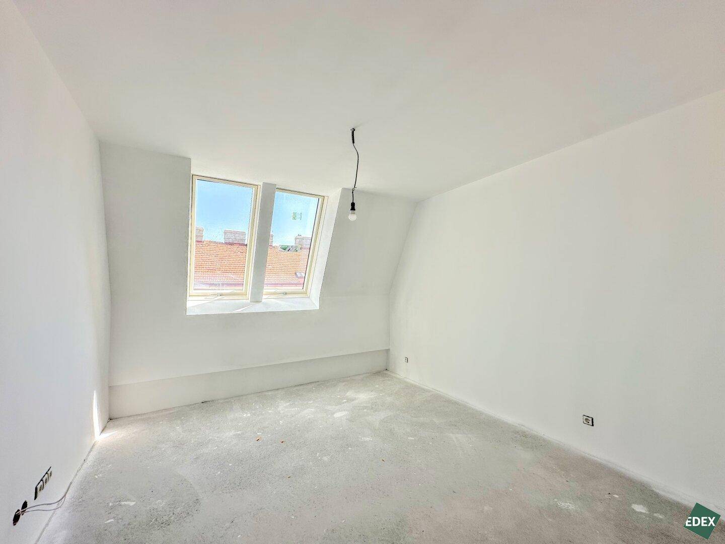 Unmöbliertes Zimmer mit weiß gestrichenen Wänden und einem Dachfenster, ideal als Schlafzimmer.