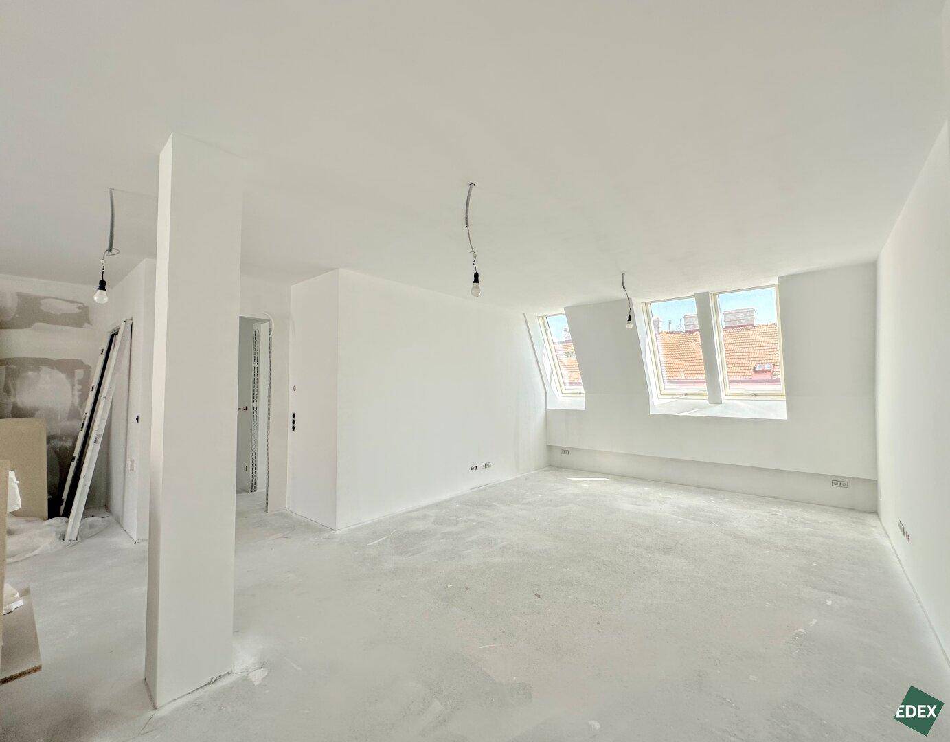 Großer, unmöblierter Raum mit Säule, weißen Wänden und Dachfenstern, bereit für den Ausbau.