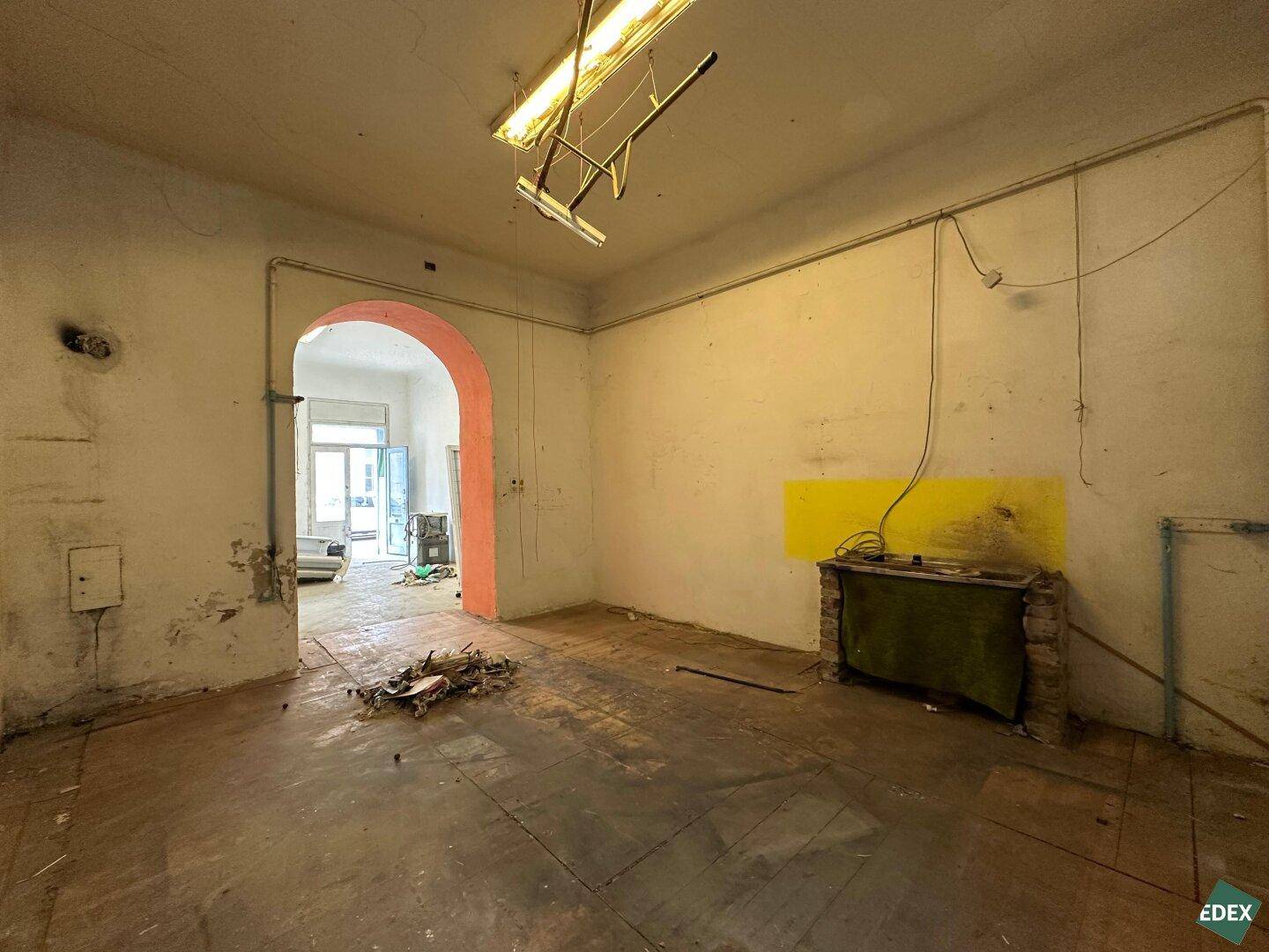 Unmöblierter Raum in Renovierung mit sichtbaren Gebrauchsspuren und alten Installationen.