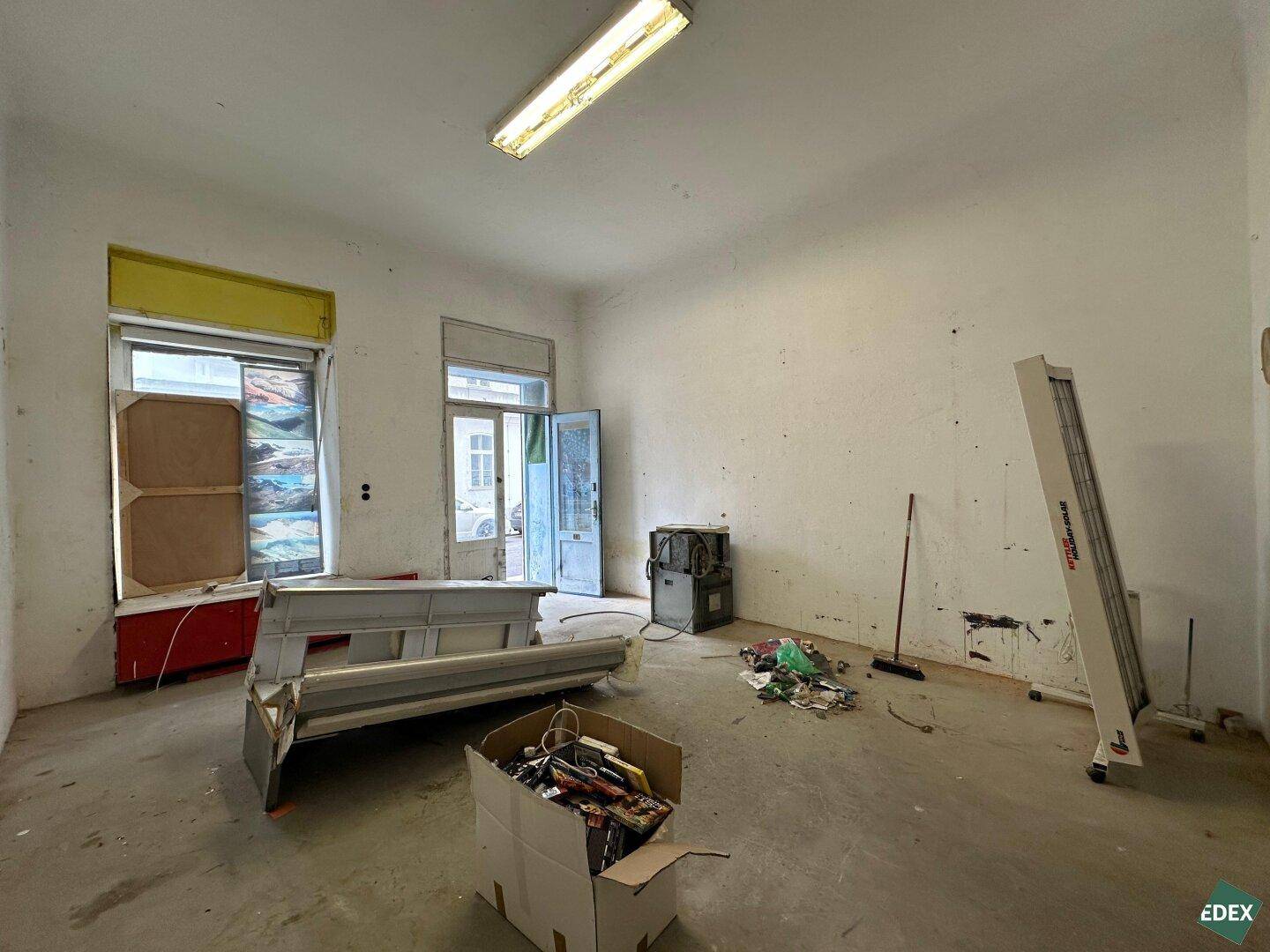 Renovierungsbedürftiger Raum mit alten Fenstern und Baustellenmaterialien.