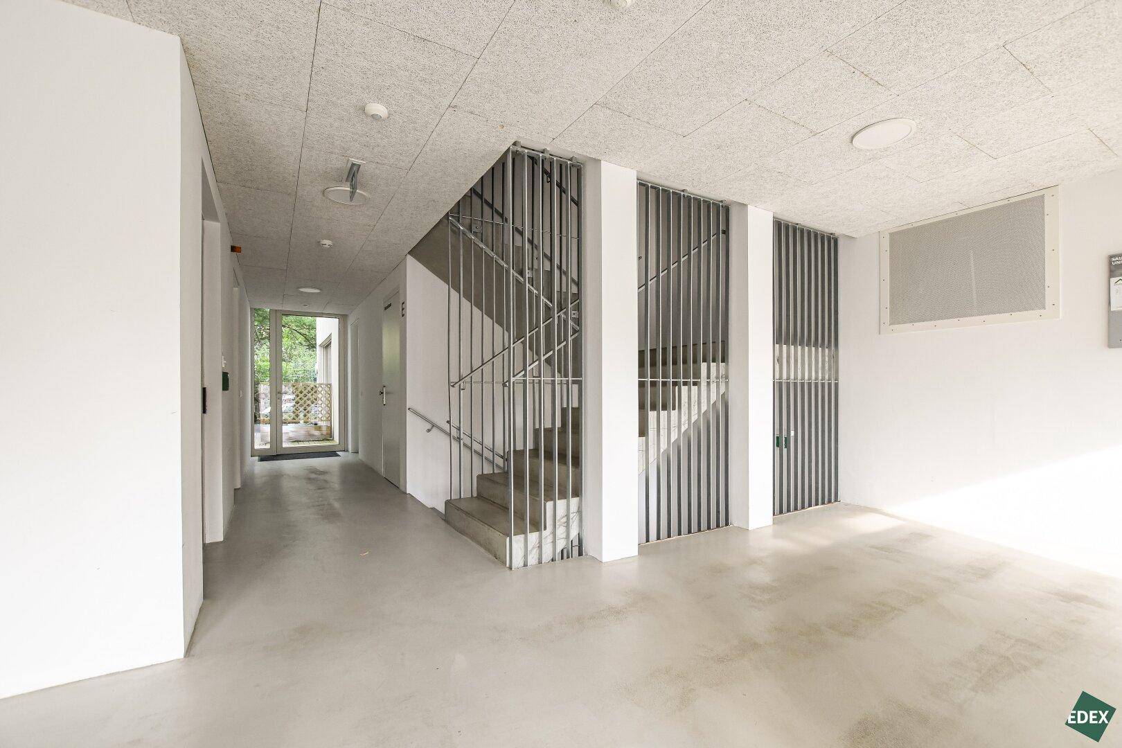 Geräumiger Flur im Gebäude mit Treppenhaus und minimalistischem Design, hell und funktional gestaltet.