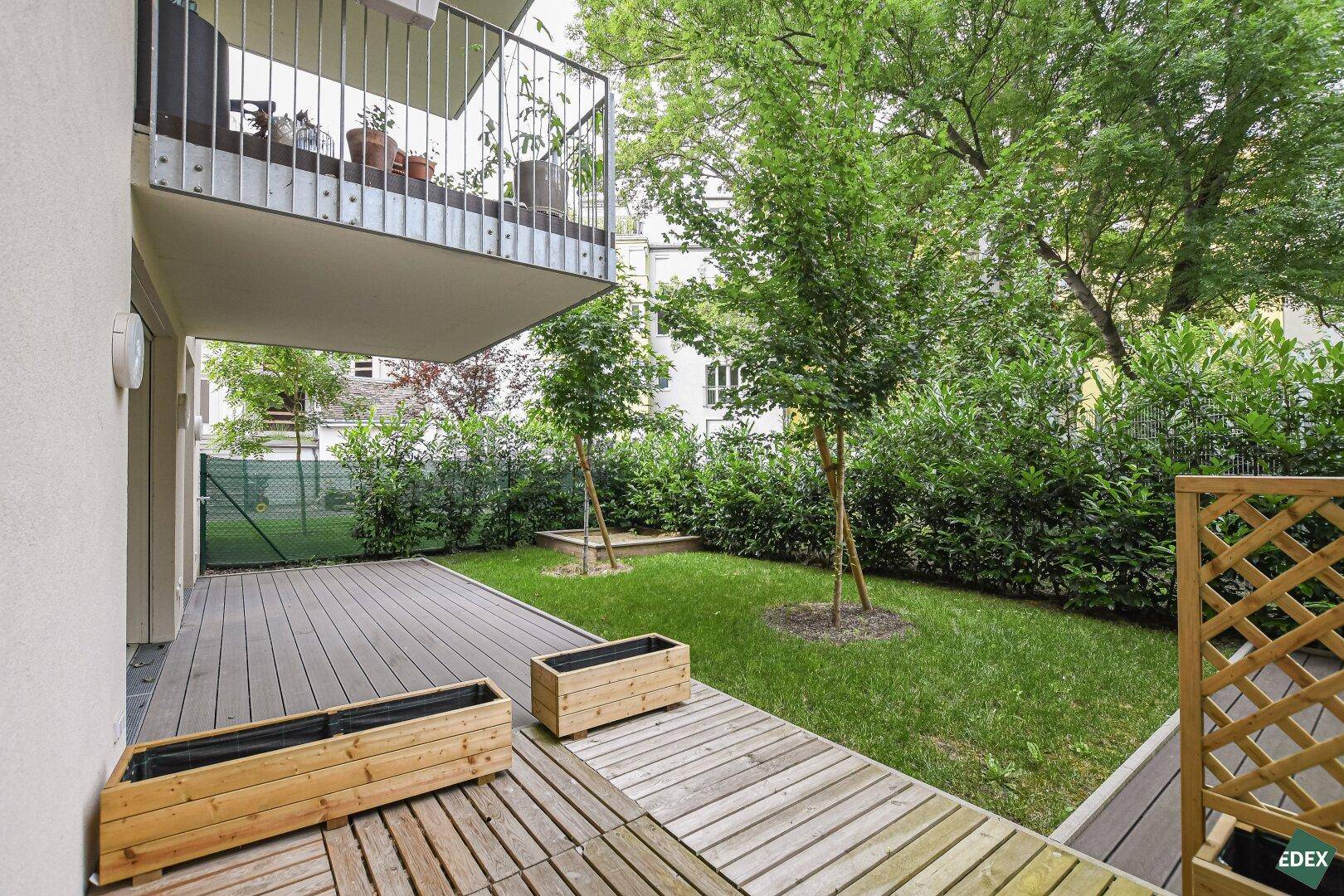Erdgeschoss-Terrasse mit Holzdeck, Rasenfläche und Zugang zu einem kleinen Garten.