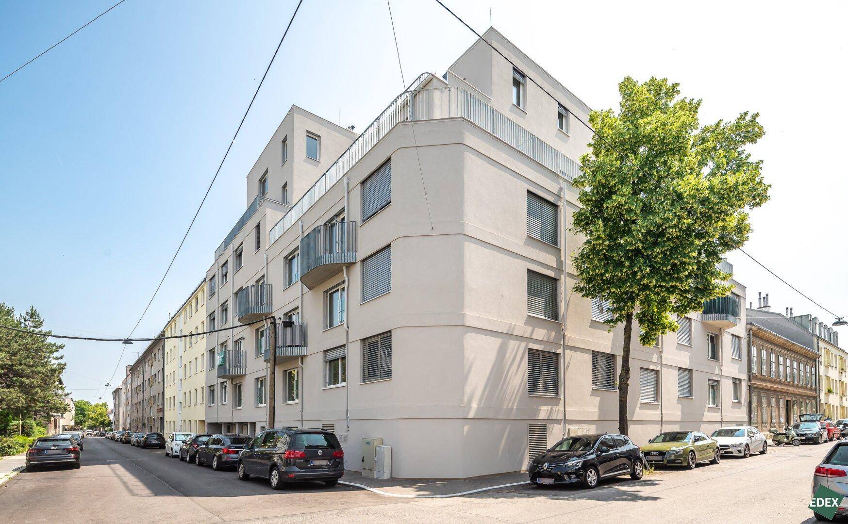 Moderne Wohnanlage mit Balkonen und großen Fenstern an einer ruhigen Straße.