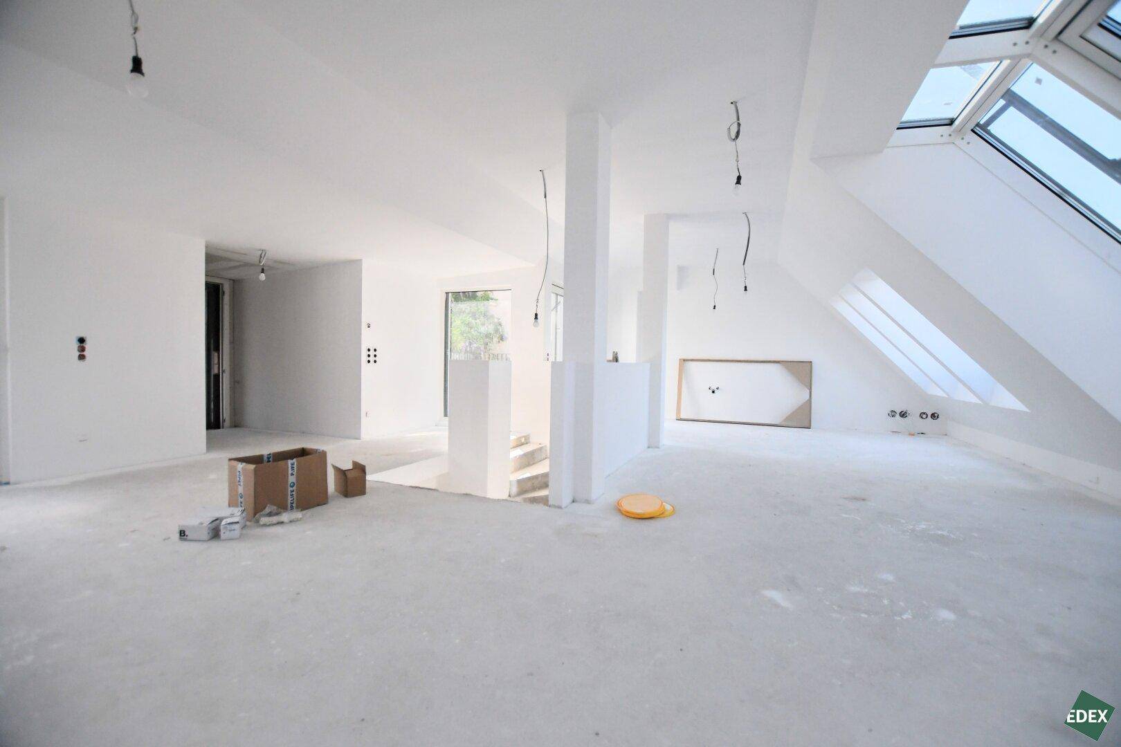 Großer Rohbau im Dachgeschoss mit offener Raumgestaltung und viel Tageslicht durch die Fenster.
