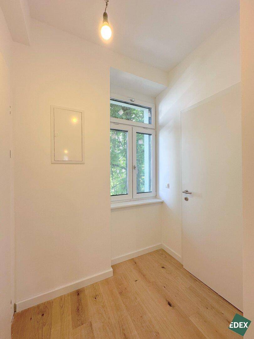 Schmaler Flur oder kleiner Raum mit Fenster und Holzboden, bietet natürlichen Lichteinfall.