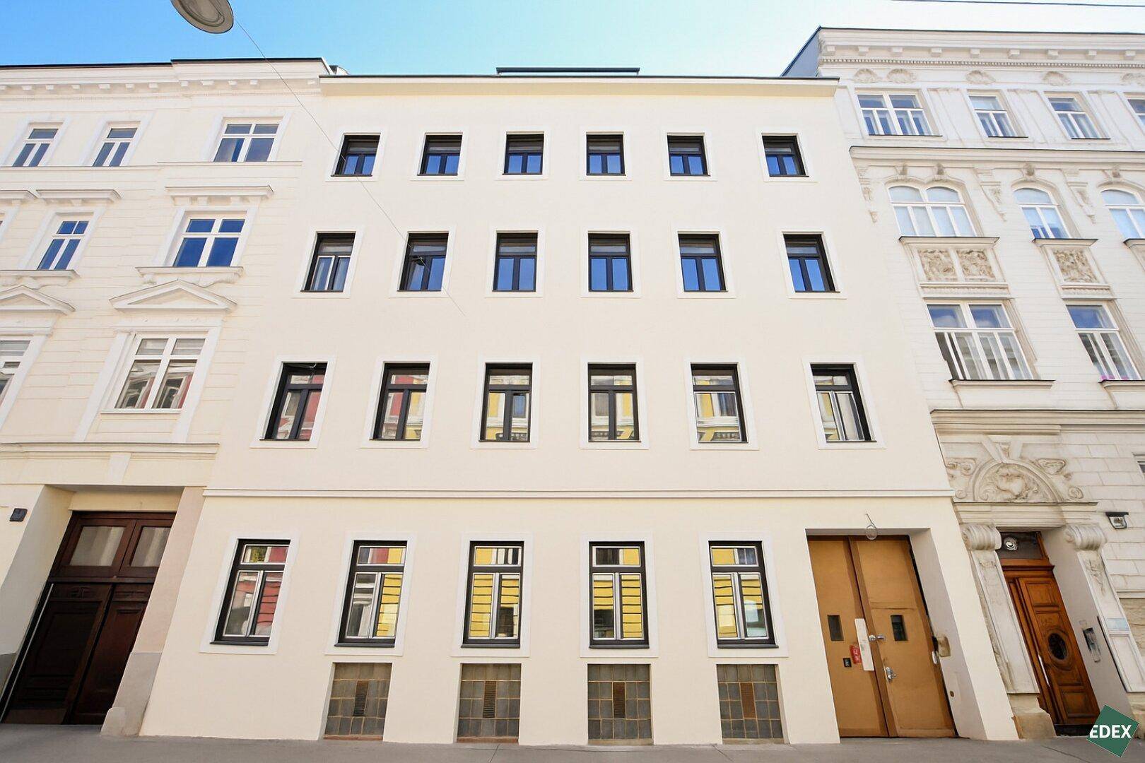 Renovierte Fassade eines Mehrfamilienhauses mit klassischen und modernen Elementen.