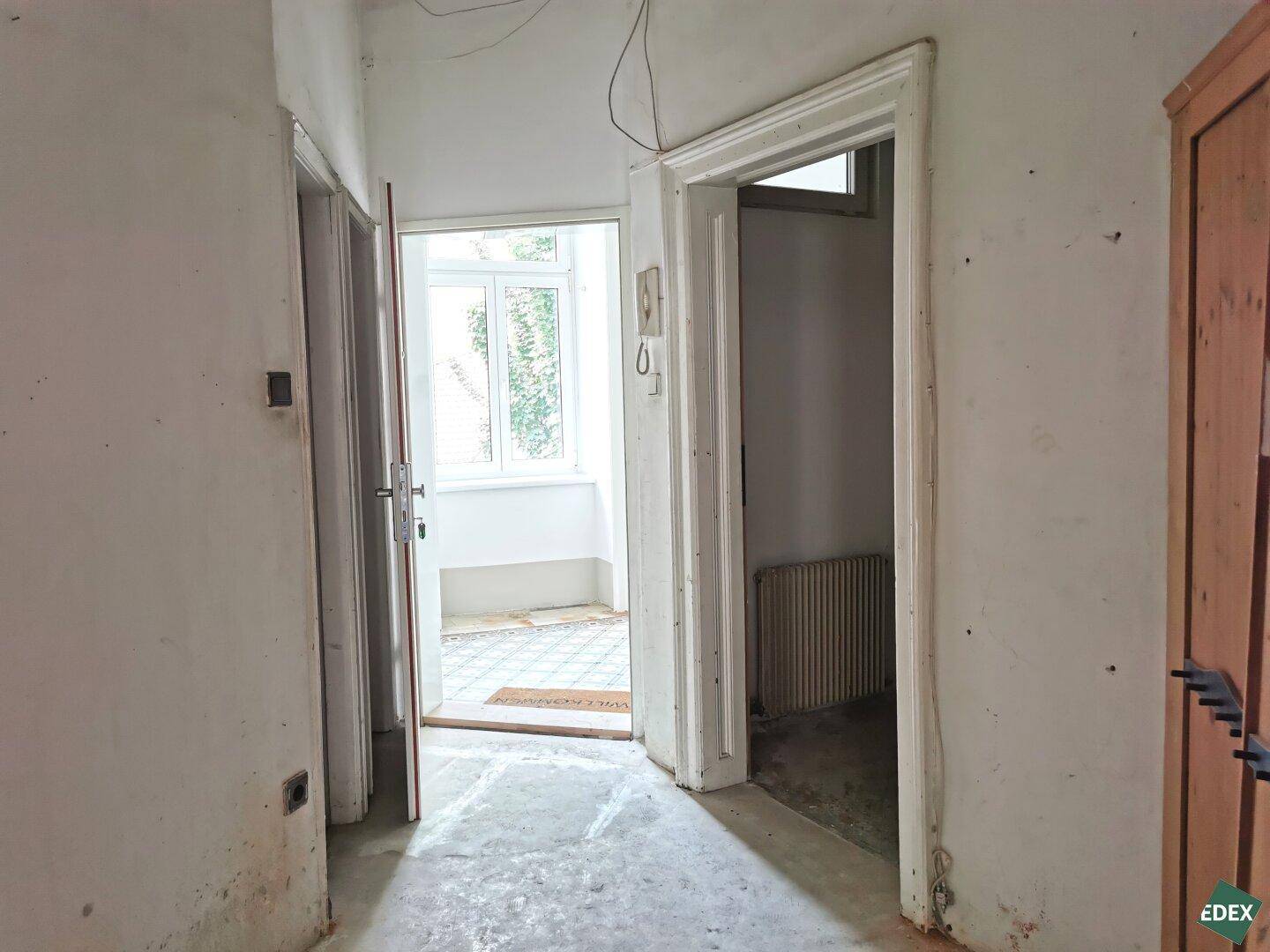 Heller Flur mit Zugang zu einem verglasten Bereich, der als Wintergarten oder Loggia dient.