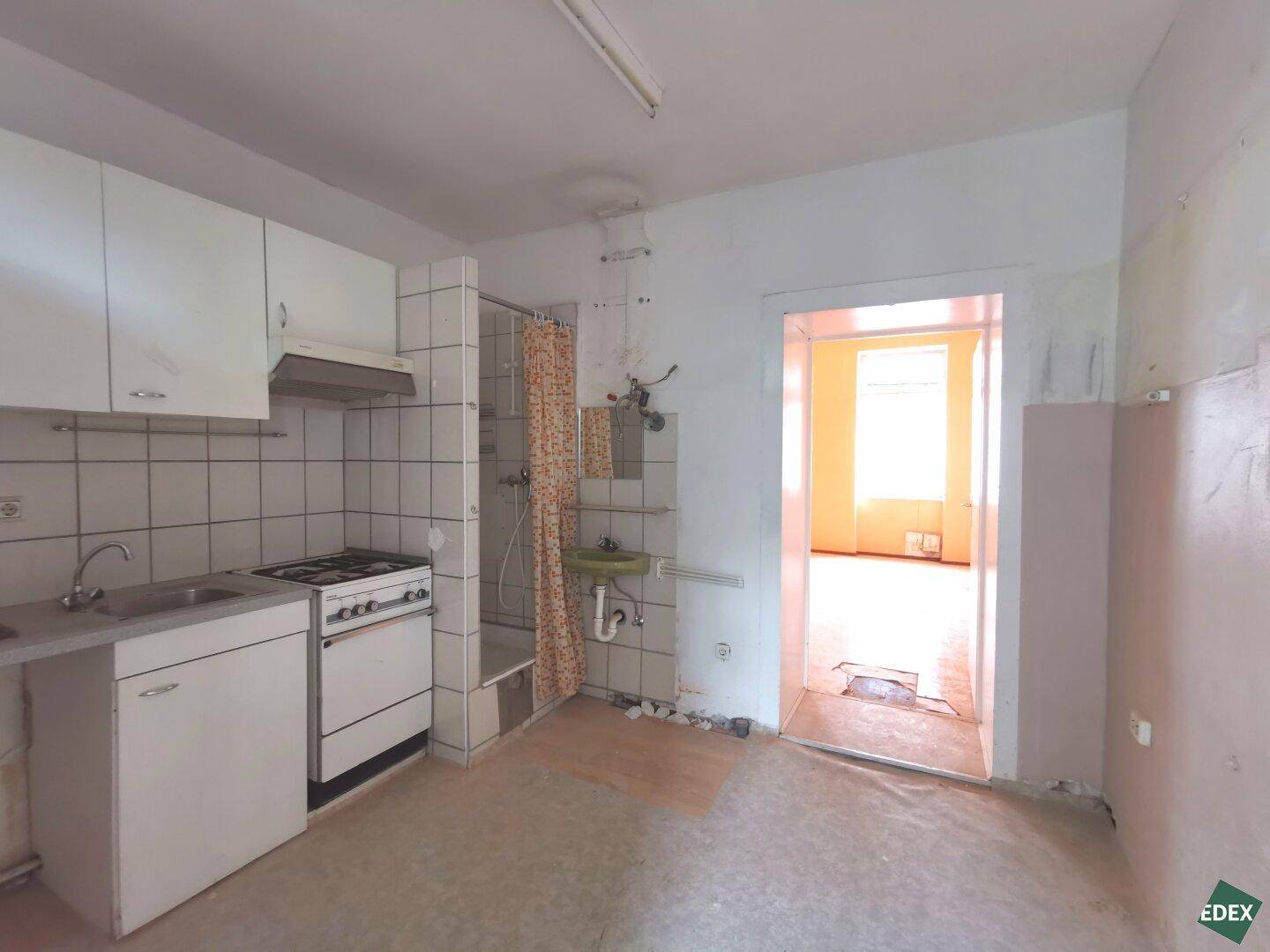 Kleine Küche mit integrierter Dusche und Gasherd, ideal für ein Studio-Apartment.